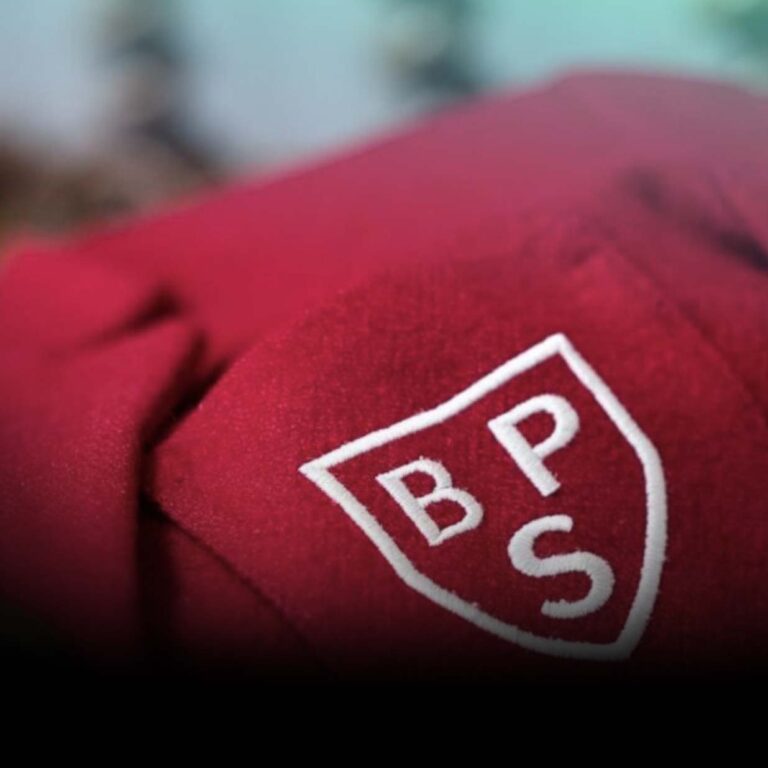 Close-up of red fabric with a white shield-shaped emblem containing the letters BPS inside.