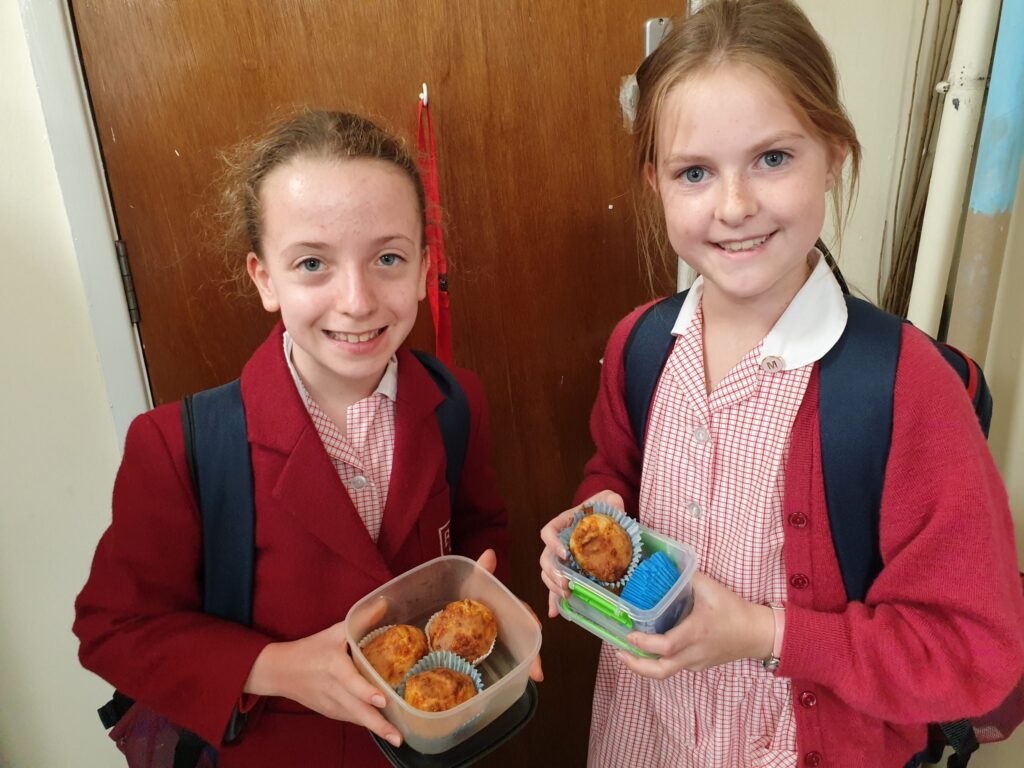 students holding baked muffins