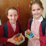 students holding baked muffins