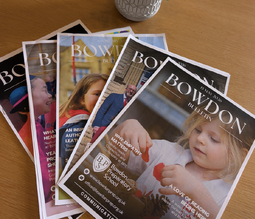 Fanned Bowdon Bulletin magazines spread on a wooden table.